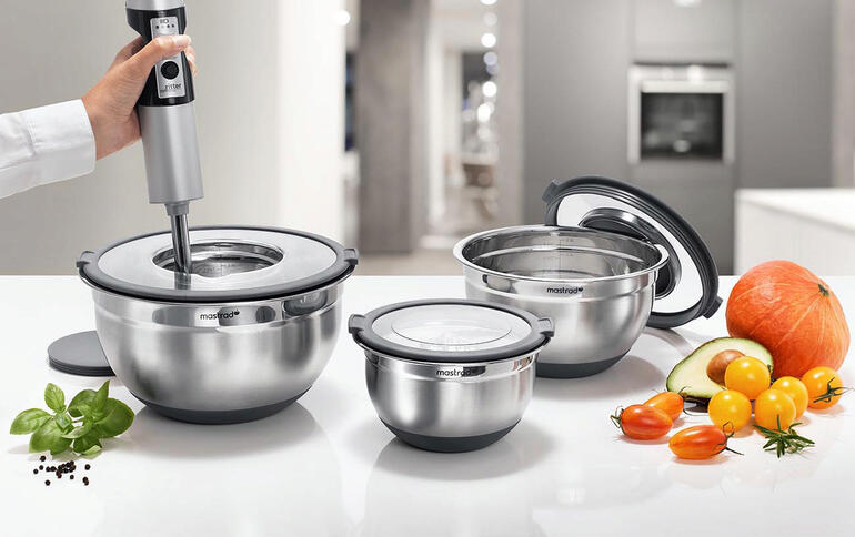 Drei Edelstahl-Schüsseln in verschiedenen Größen mit Küchenutensilien auf einer Arbeitsfläche.