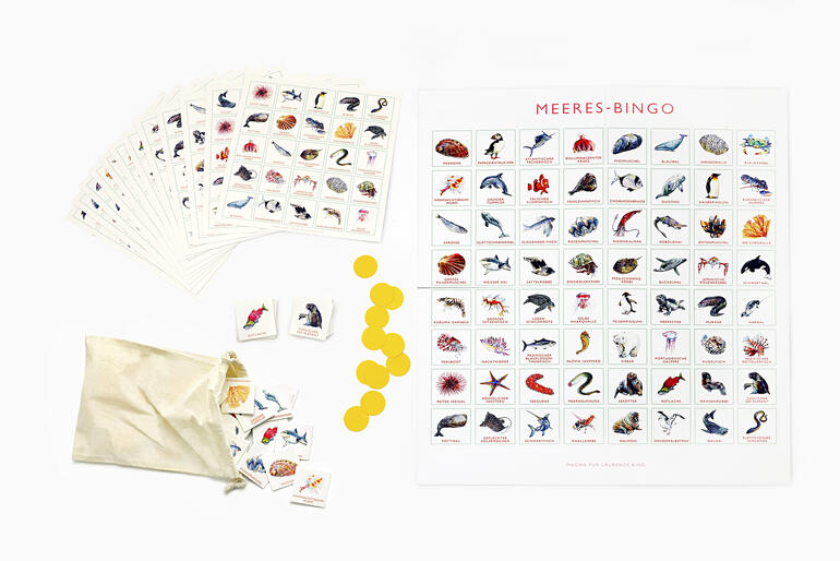 Enthält 12 Bingo-Karten, 64 Spielkärtchen, 200 Markierungs-Chips, Spielbrett, Stoffbeutel, Broschüre. Spielmaterial für Meeres-Bingo auf einem weißen Tisch.