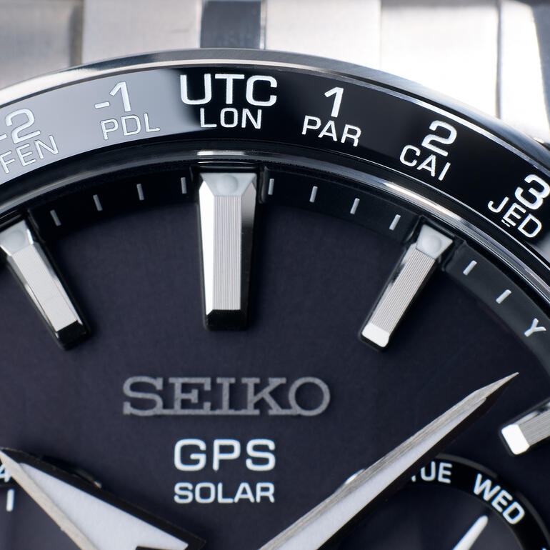 Auf der Keramiklünette sind 39 Zeit-Zonen synchron ablesbar. Nahaufnahme des Zifferblatts einer GPS-Uhr.