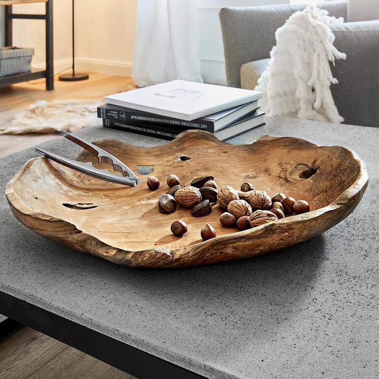 Teakholz-Schale mit Nüssen und einer Zange auf einem Tisch.