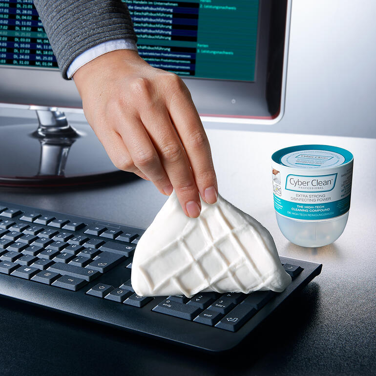 Hand greift nach Cyber Clean Professional zur Reinigung einer Tastatur.