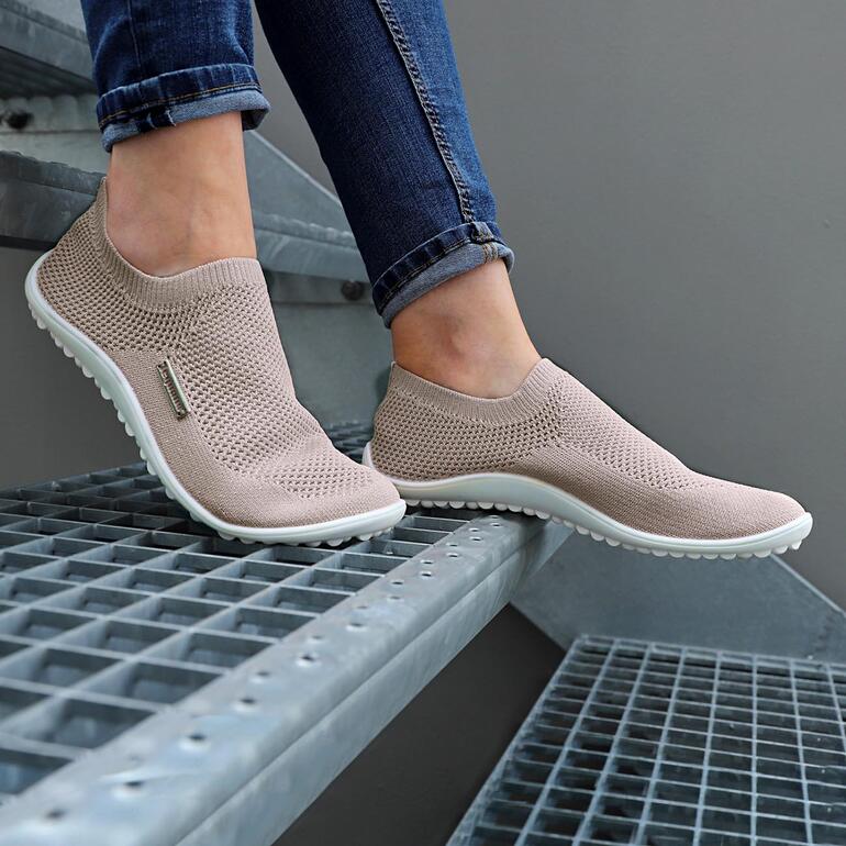 Rosé Beige Barfuß-leguano® Slipper an einem Fuß auf einer Treppe.