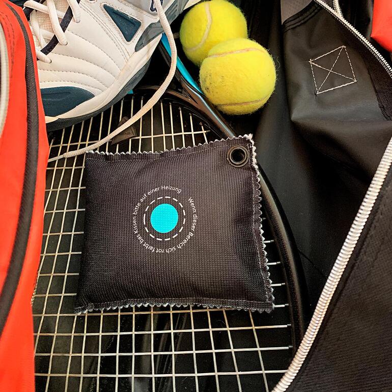 Autoentfeuchter liegt in einer Sporttasche neben Tennisbällen.