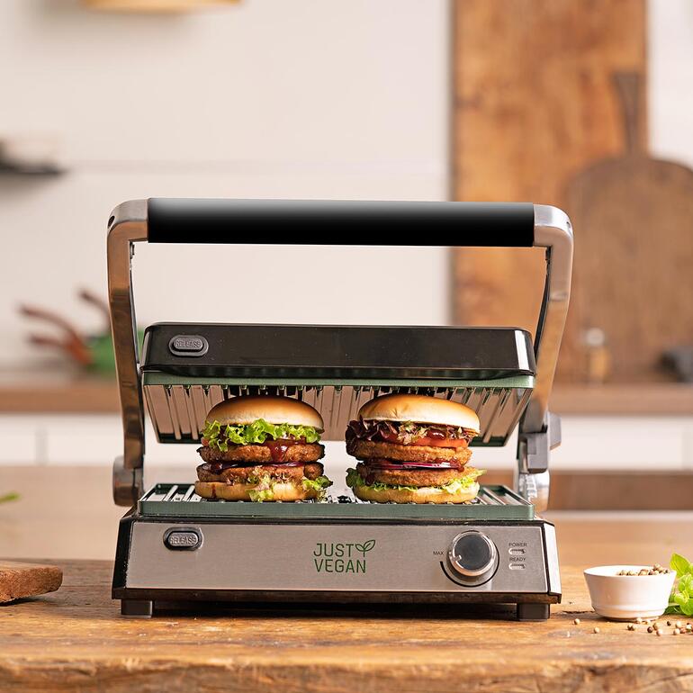 Kontaktgrill CeraVegan mit zwei Burgern, geöffnet auf einem Holzbrett.