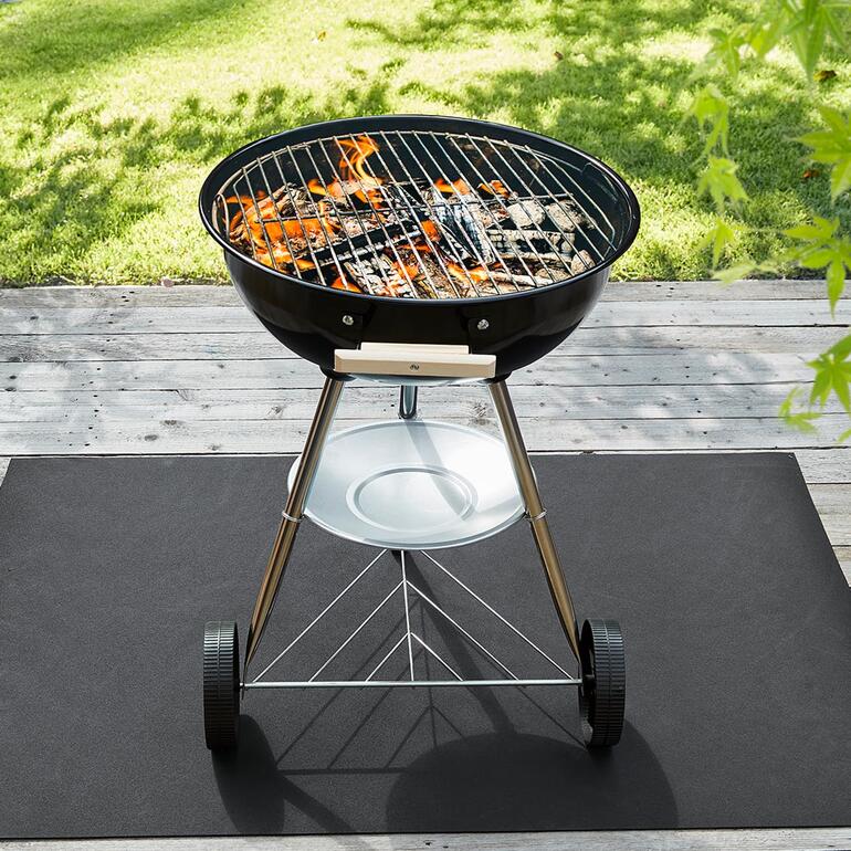 Grill auf einer Recycling-Bodenschutzmatte im Freien.