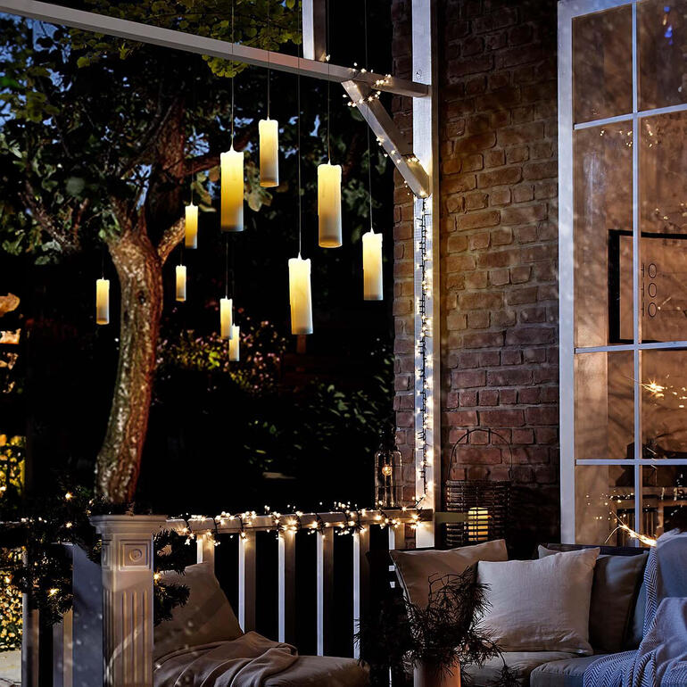 Ein bezaubernder Blickfang auch auf Ihrer Terrasse oder im Garten. Hängende LED-Kerzen auf einer Terrasse mit Lichterkette.