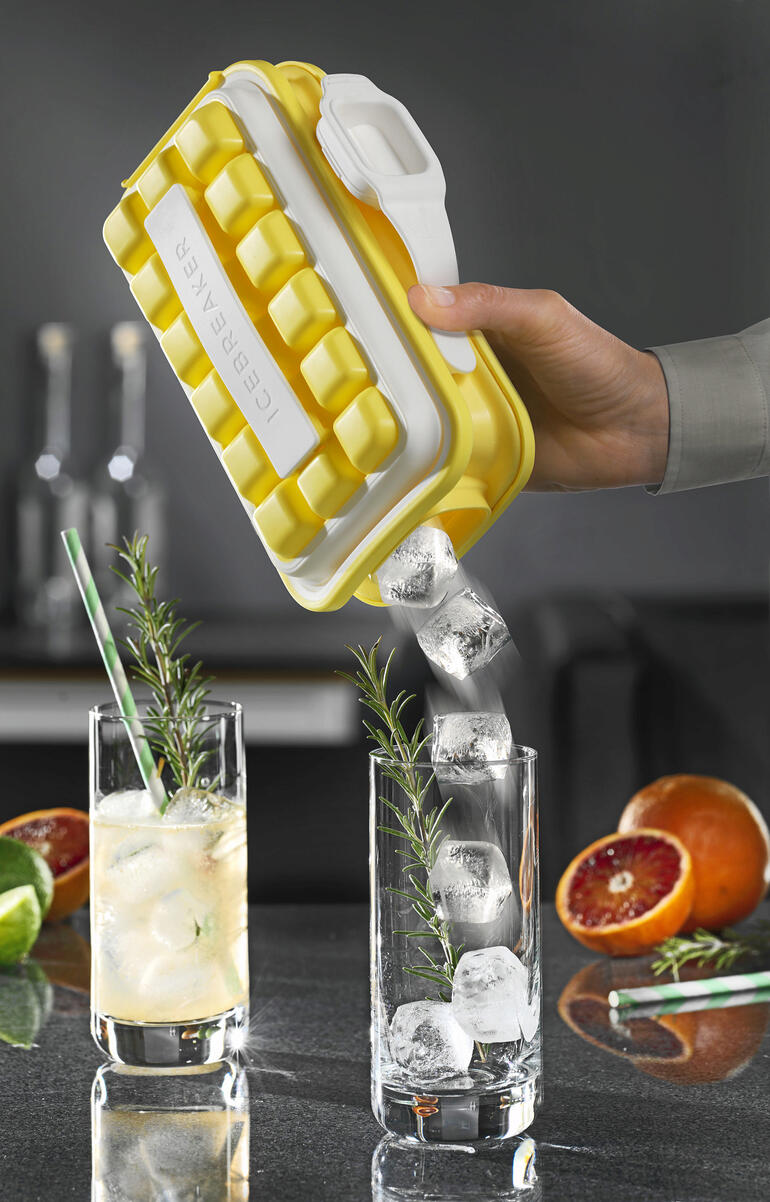 Hand hält Ice-Pop Eiswürfelform, Eiswürfel fließen in ein Glas mit Getränk.