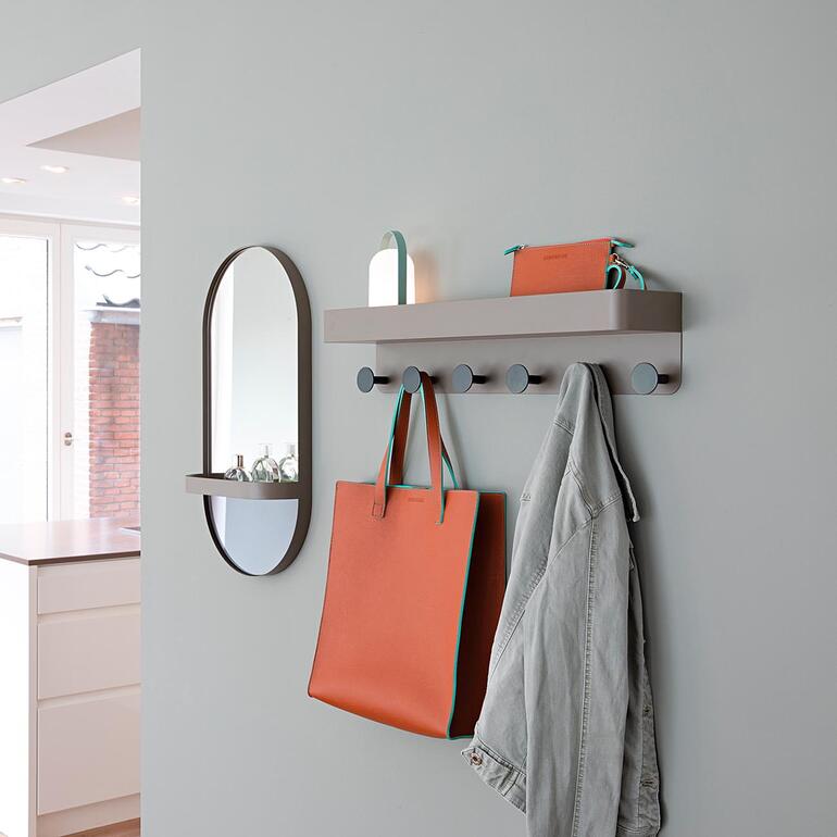 Wandgarderobe mit Ablage und Holzdetails, Taschen und Jacken hängen daran.