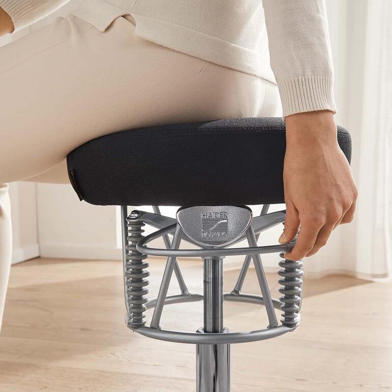 Ob Sie sich nach vorne, hinten oder zur Seite bewegen – Bioswing unterstützt jede Position perfekt. Detailaufnahme der Hand einer Frau, die am ergonomischen Stuhl einen Regler einstellt.