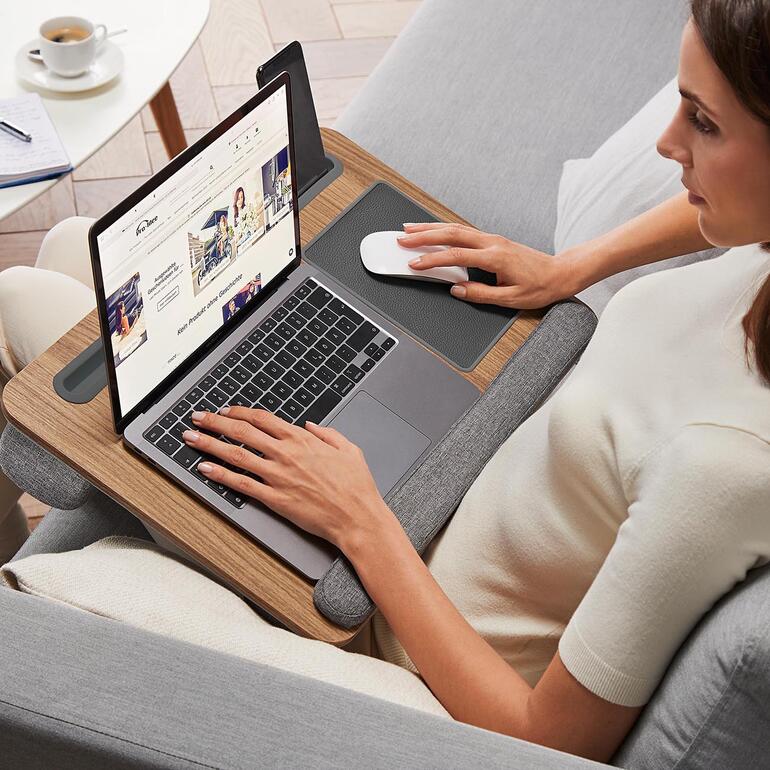 Frau sitzt mit einem Laptop auf einem bequemen Lesekissen.