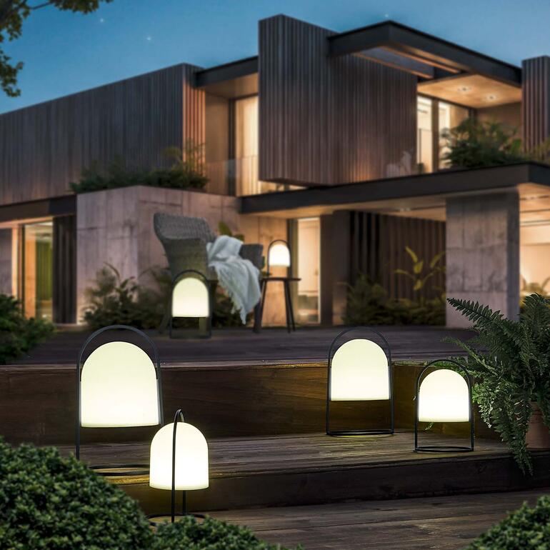 Solar-Laterne in einem Garten vor einem modernen Haus bei Nacht.