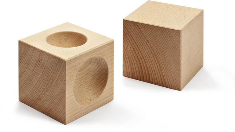 NUSSKUBUS Zwei Holzwürfel, einer mit Aussparung für Nüsse.
