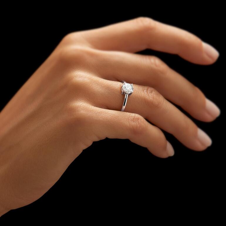 Nahaufnahme eines rhodinierten Moissanite-Rings am Finger einer Person.