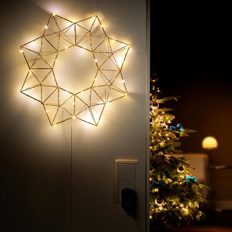 Pyramiden-Lichterstern an der Wand, beleuchtet mit warmem Licht.