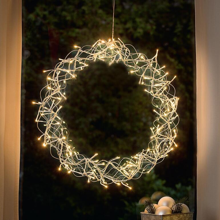 LED-Deko-Kranz mit leuchtenden Lichtern in einem Fenster.