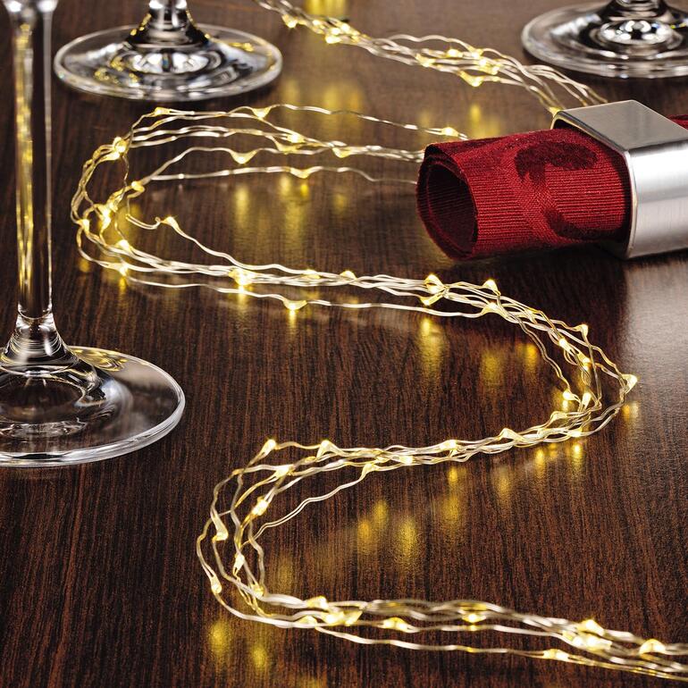 Ihre Engelshaar-Lichterkette ist flexibel formbar und vielseitig einsetzbar. Engelshaar-Lichterkette auf einem Tisch mit Weingläsern.