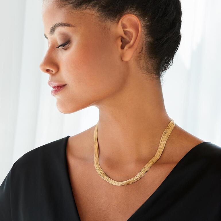 Frau mit goldfarbener Ankerkette, die elegant um ihren Hals fällt.