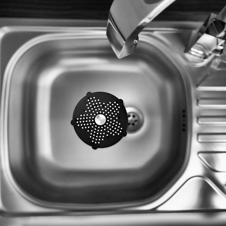 Das handtellergroße Abflusssieb ist perfekt in der Spüle, Dusche, Wanne, über dem Bodenabfluss, ... Schwarzes Abflusssieb schwebt über einer Spüle