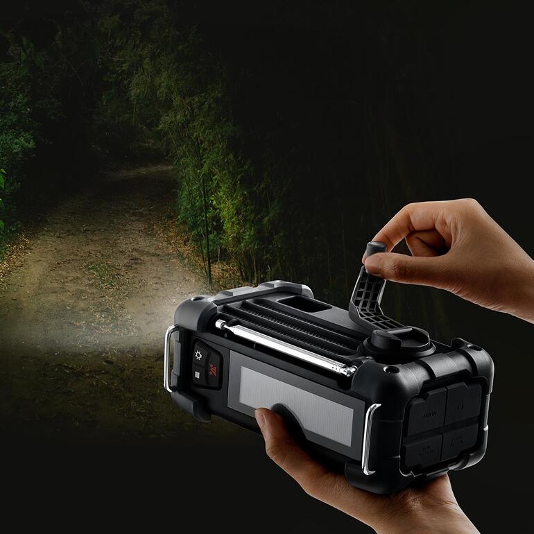 Gleichzeitig auch Ihre helle LED-Hand- und Standleuchte mit SOS-Funktion. Hand an einem digitalen Survival-Radio mit Licht in dunkler Umgebung.