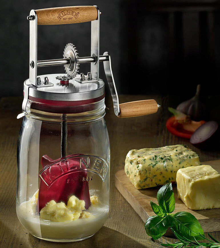 Butterglas mit Handkurbel auf einem Holztisch mit Butter
