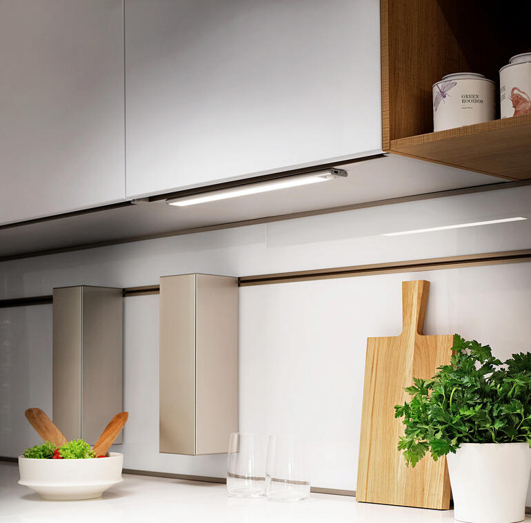 Variable Akku-Lichtleiste montiert unter einem Küchenschrank mit frischen Zutaten auf der Arbeitsfläche.