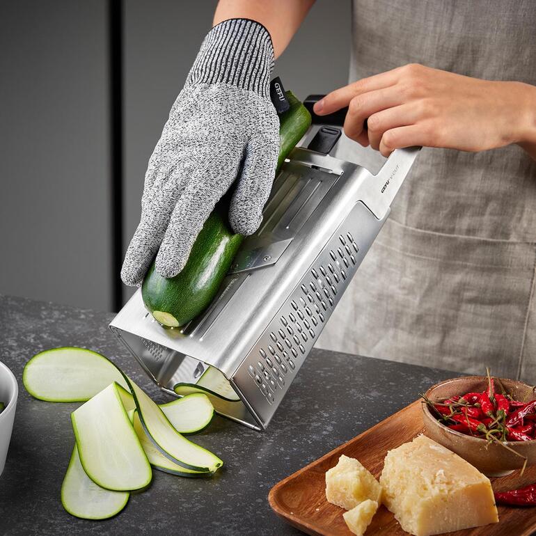 Gelaserte Klingen schneiden das Reibgut butterweich und präzise. Hand an einer Turmreibe, die eine Zucchini zum Raspeln verwendet.