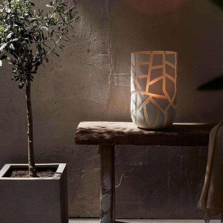 Als Vase oder Windlicht vielseitig nutzbar. Vase auf einem Tisch, beleuchtet, mit dekorativen Ausschnitten