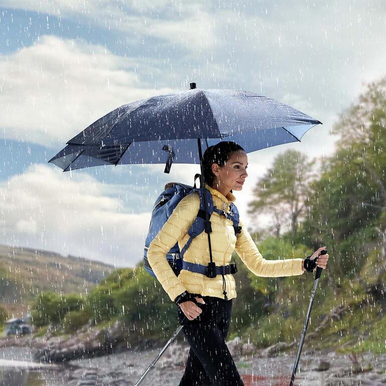 Marine Frau mit freihändigem Rucksackschirm geht bei Regen.