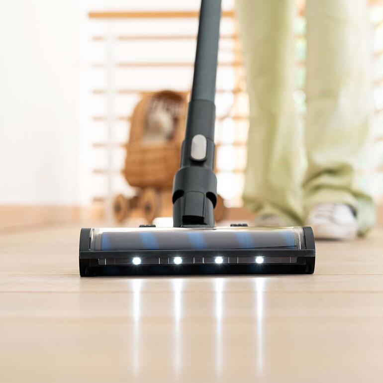 Elektrobürste für Hart- und Teppichböden mit LED-Beleuchtung. Nahaufnahme der Staubsaugerdüse auf einem Bodenbelag.