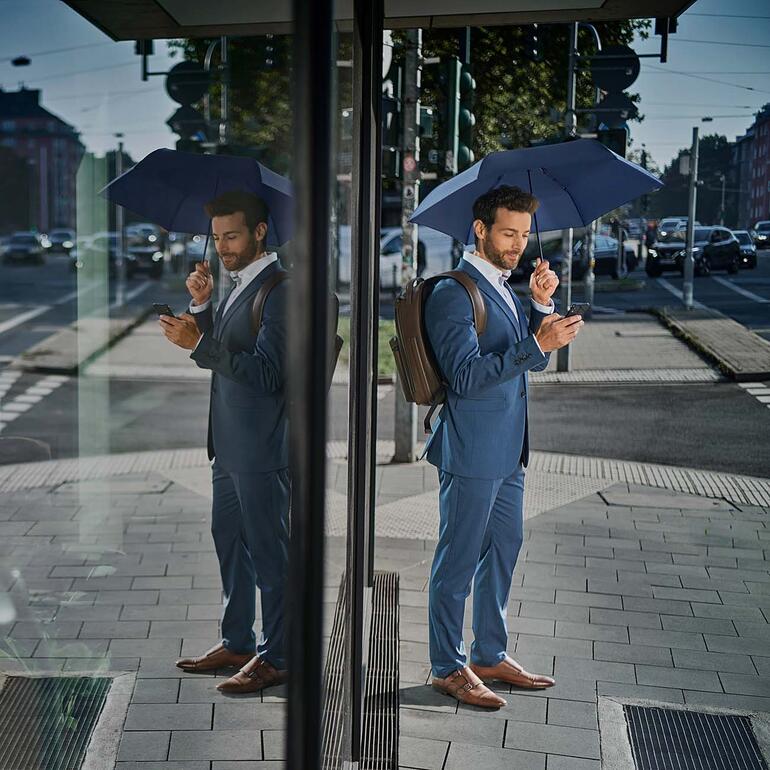 Mann im Anzug mit einem ultraleichten Schirm auf der Straße