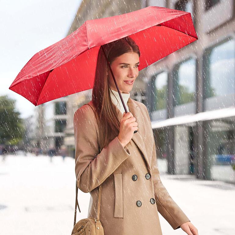 Rot Frau mit rotem ultraleichten Schirm bei Regen