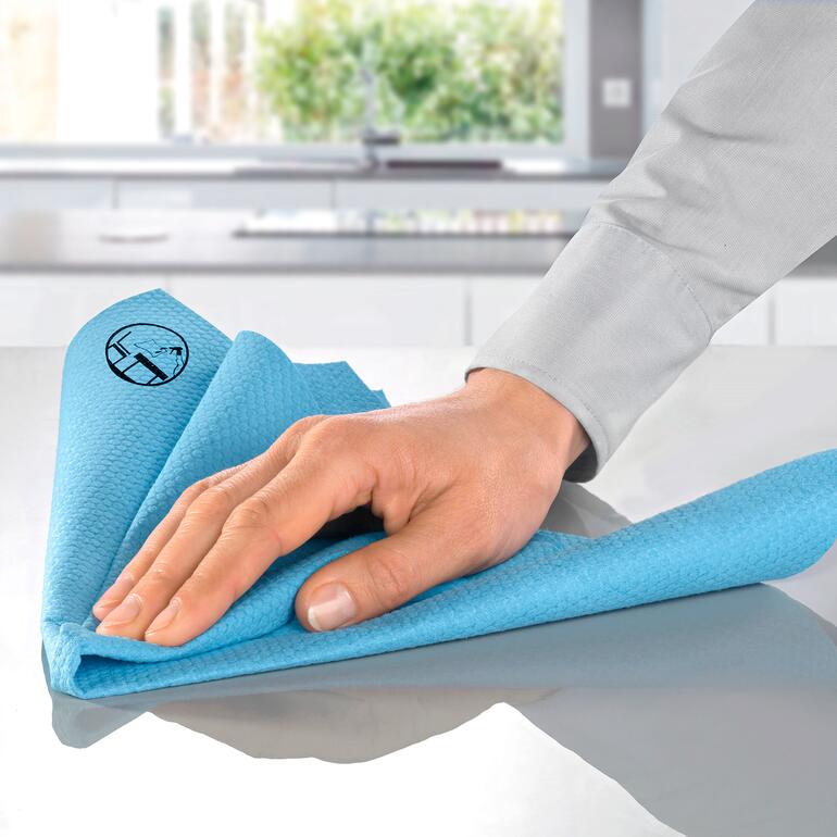 Hand wischt mit antibakteriellem Reinigungstuch über eine Oberfläche.