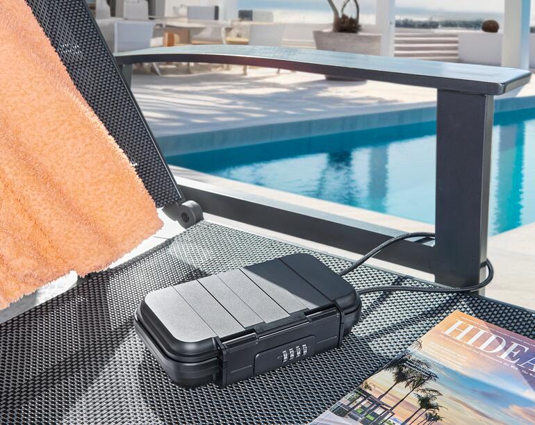 Die ABS-Box ist nahezu unverwüstlich und schließt Ihre Wertsachen luftdicht und wassergeschützt ein (Schutzart IPX6). Mobiler Safe auf einer Liege am Pool