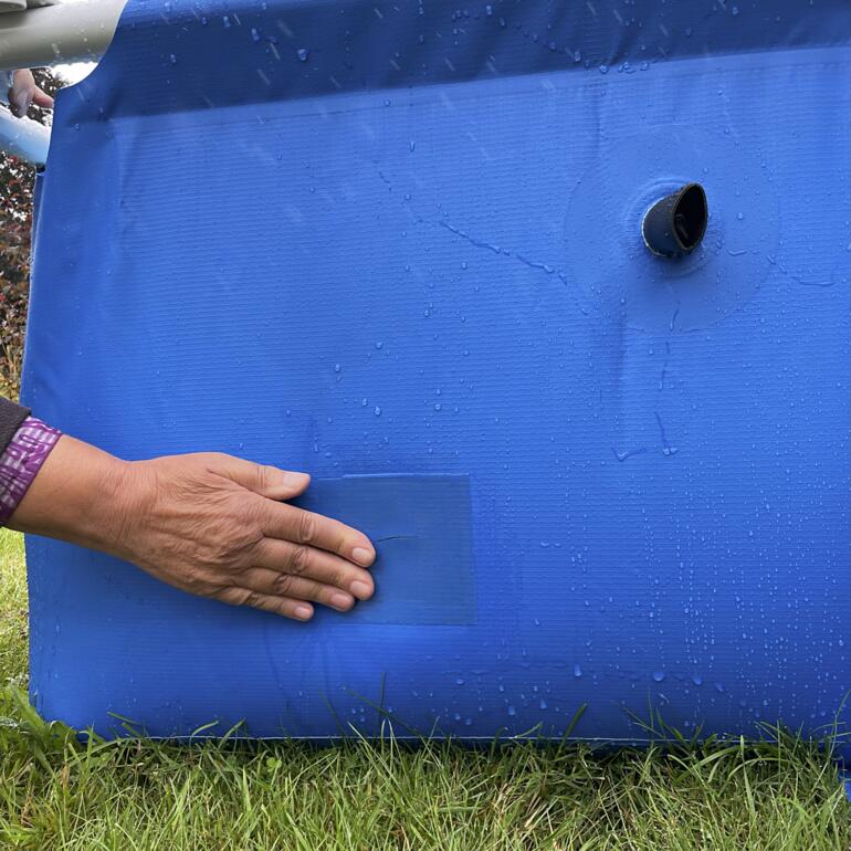 Person klebt Unterwasser-Klebeband an ein blaues Poolmaterial.