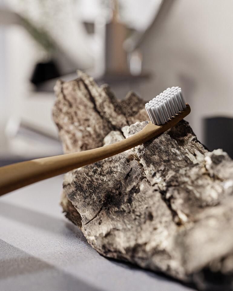 Der Bürstenkopf besteht aus 6.750 haarfeinen Thermoplast-Filamenten und der Griff ist mit dem natürlichen Holzbestandteil Lignin gefertigt. Holzzahnbürste auf einem schlichten Hintergrund.