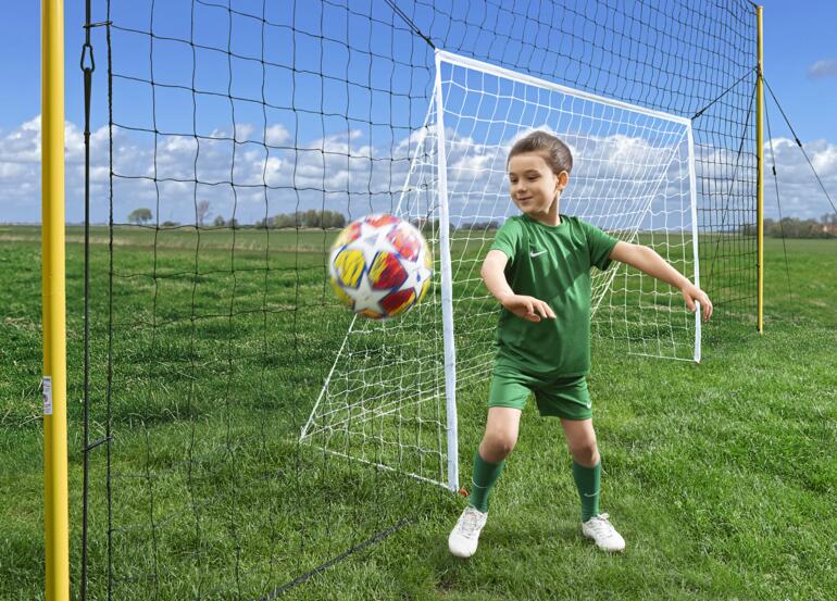 Das 2,4 x 1,4 m große Tor ist im Fangnetz zentral integriert – so werden die Schüsse neben und übers Tor bequem aufgefangen. Tor mit Fangnetz, Kind spielt mit einem Ball