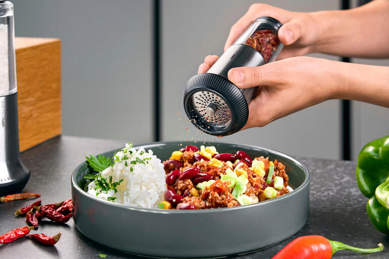 Chili-Schneider X-Plosion® wird über einen Teller mit Reis und Gemüse gehalten