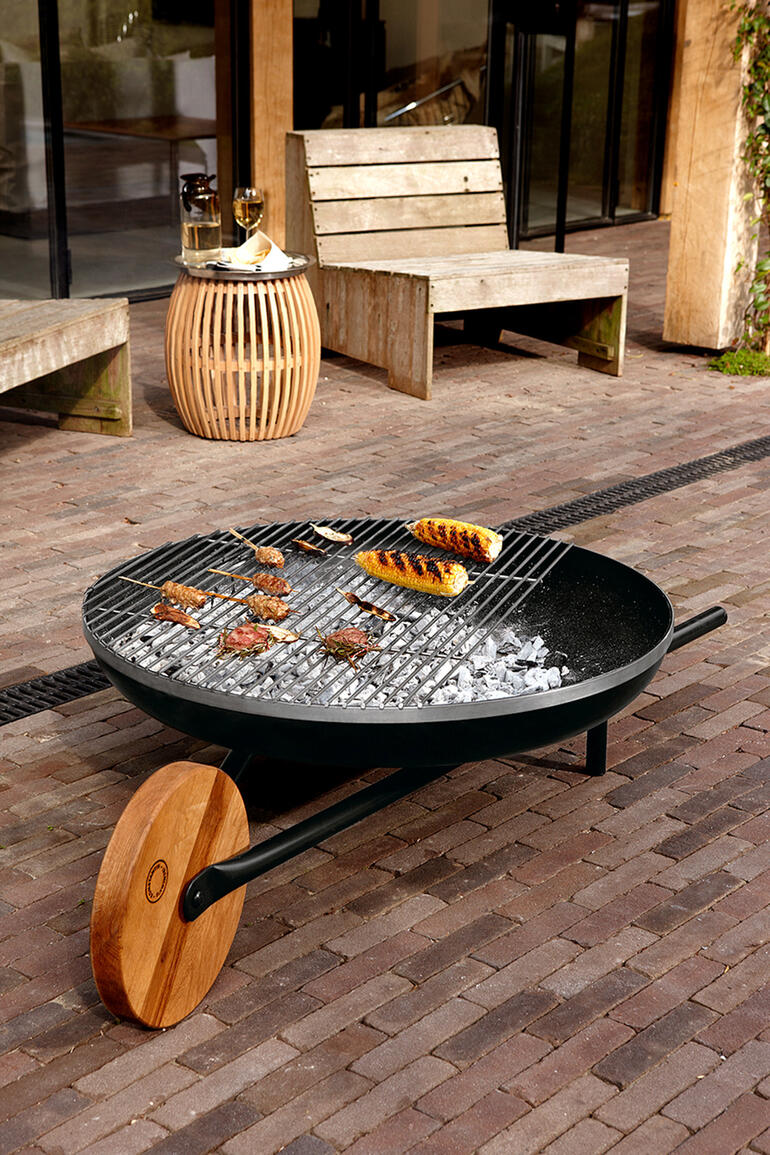 Feuerschale mit Grill, auf der Fleisch und Gemüse gegrillt werden.