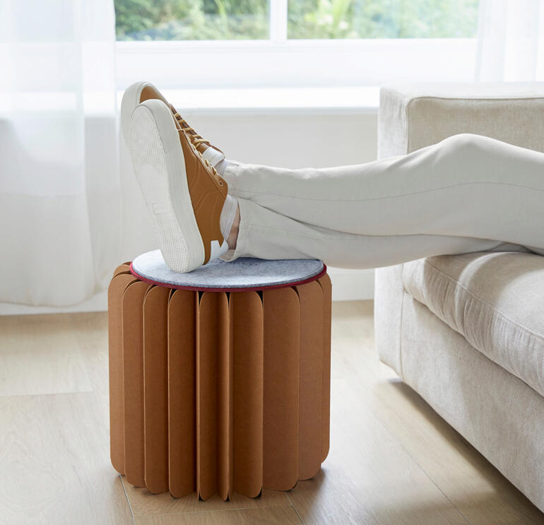 Frau mit einem Bookniture-Hocker, der als Fußablage verwendet wird.