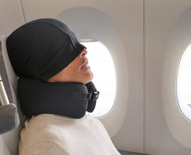 Komfort-Reisekissen mit Kapuze Mann mit Komfort-Reisekissen und Kapuze im Flugzeug
