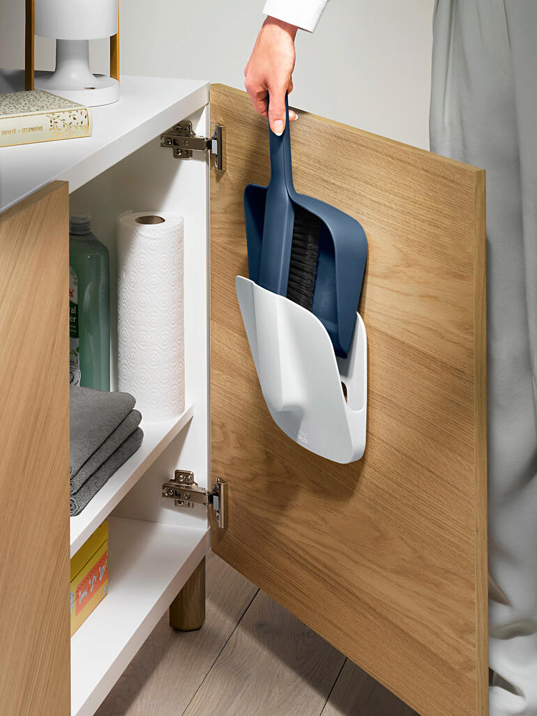 Kehrset mit Wandhalter wird aus einem Schrank genommen.