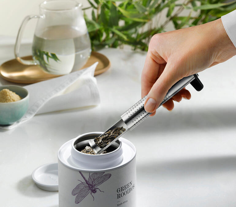 Hand greift nach dem Aroma-Langrohr-Teefilter