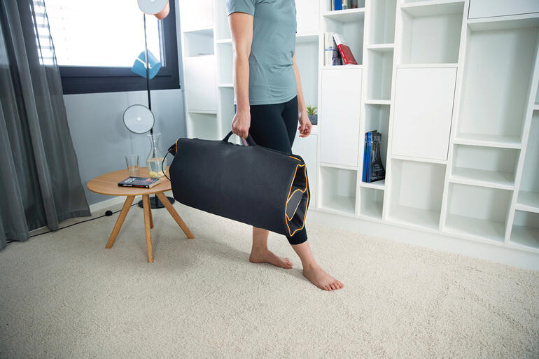 Nach Gebrauch im Nu auf Taschenformat zusammengelegt – ideal auch zum Mitnehmen. Mann trägt eine Dehn- und Massagematte in einer Tasche