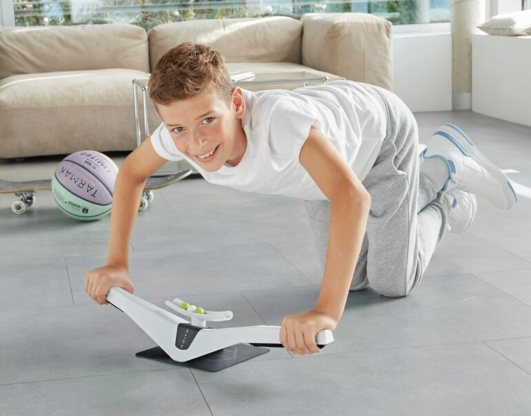 Praep® Plank-Trainer Junge übt auf dem Praep® Plank-Trainer in einem modernen Raum.