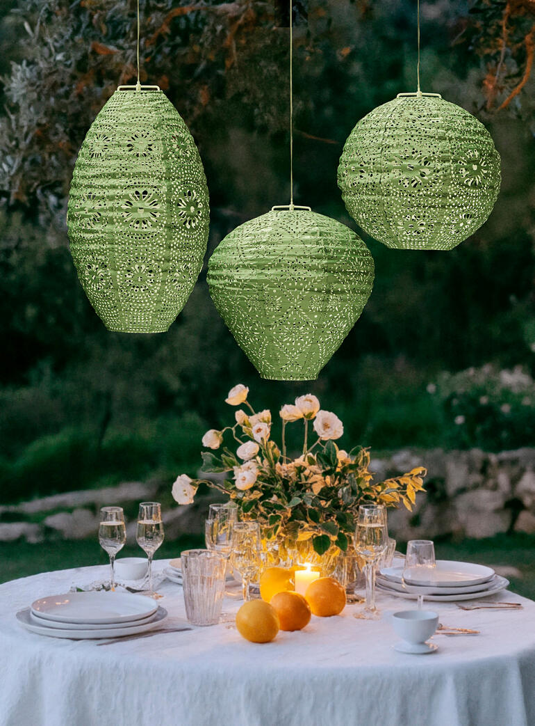 Auch unbeleuchtet sind die detailreich gearbeiteten Lampions ein zauberhafter Blickfang. Drei wetterfeste Salbeilampions mit Solar und LEDs über einem gedeckten Tisch.