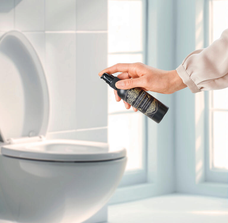 Hand sprüht Zitronen-Duft Toilettenspray auf die Toilette.