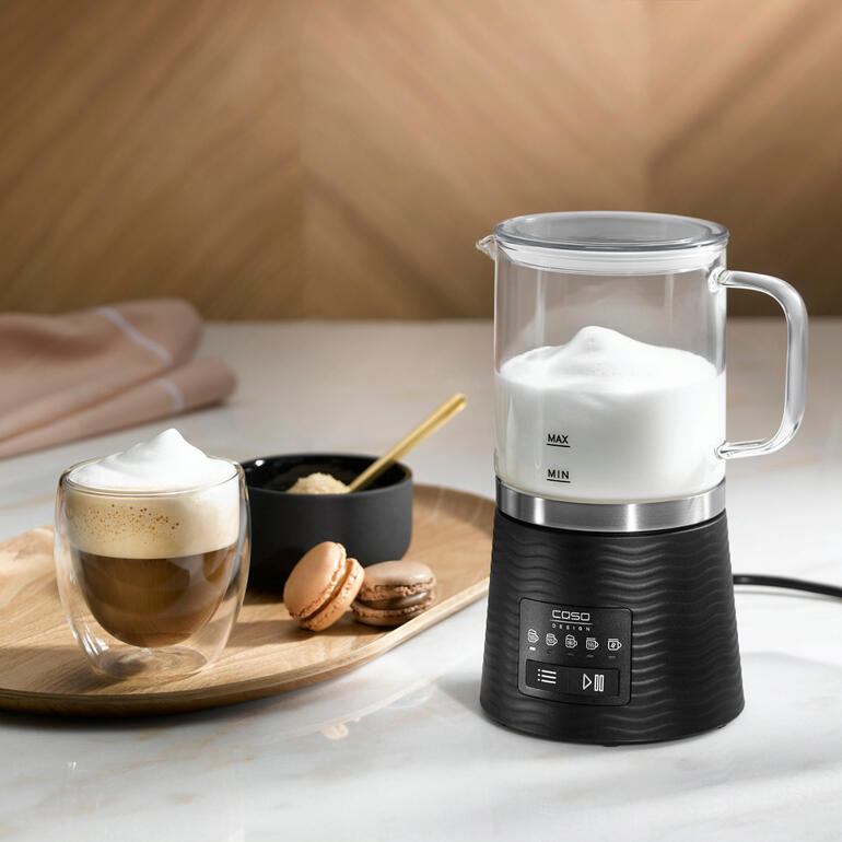 Design-Milchaufschäumer mit Milchschaum, Kaffee und Macarons