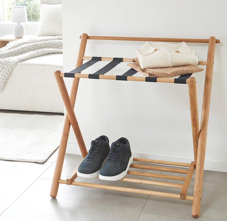 Ideal auch als Ablage für Kleidung, die noch nicht in die Wäsche, aber auch nicht mehr in den Schrank gehört. Eiche-Kofferablage mit gefalteter Kleidung und Sneakers darauf.
