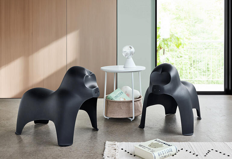 Zwei schwarze Gorilla-Hocker stehen in modernem Wohnraum mit Tisch.