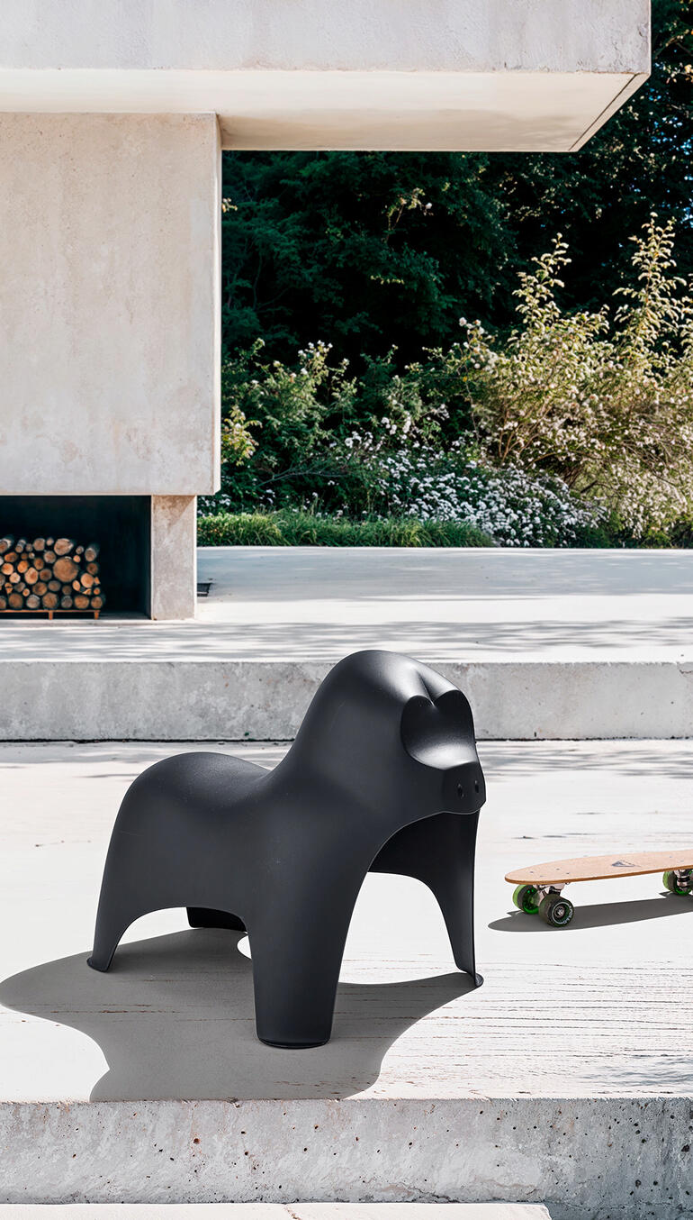 Schwarzer Gorilla-Hocker steht auf einer Terrasse neben Skateboard.